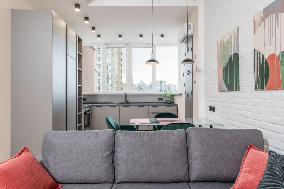 Interior of open plan apartment with soft couch in living room and dining table in modern kitchen
