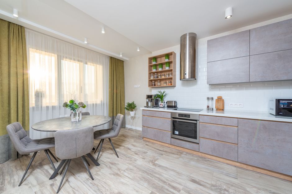 Contemporary kitchen featuring sleek cabinets, dining area, and natural lighting.