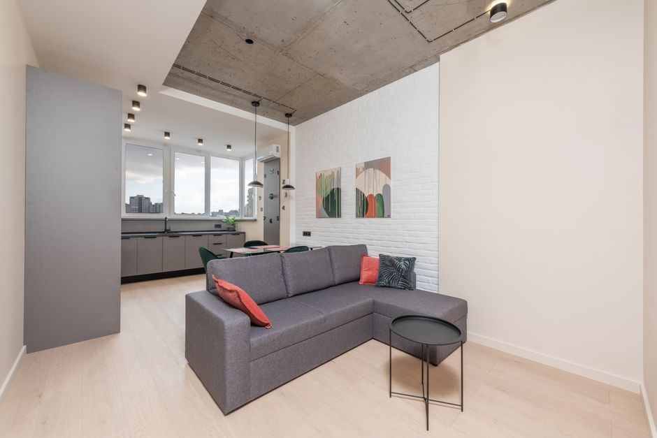 Interior of lounge with comfortable sofa and kitchen with dining table and counter in new open plan flat